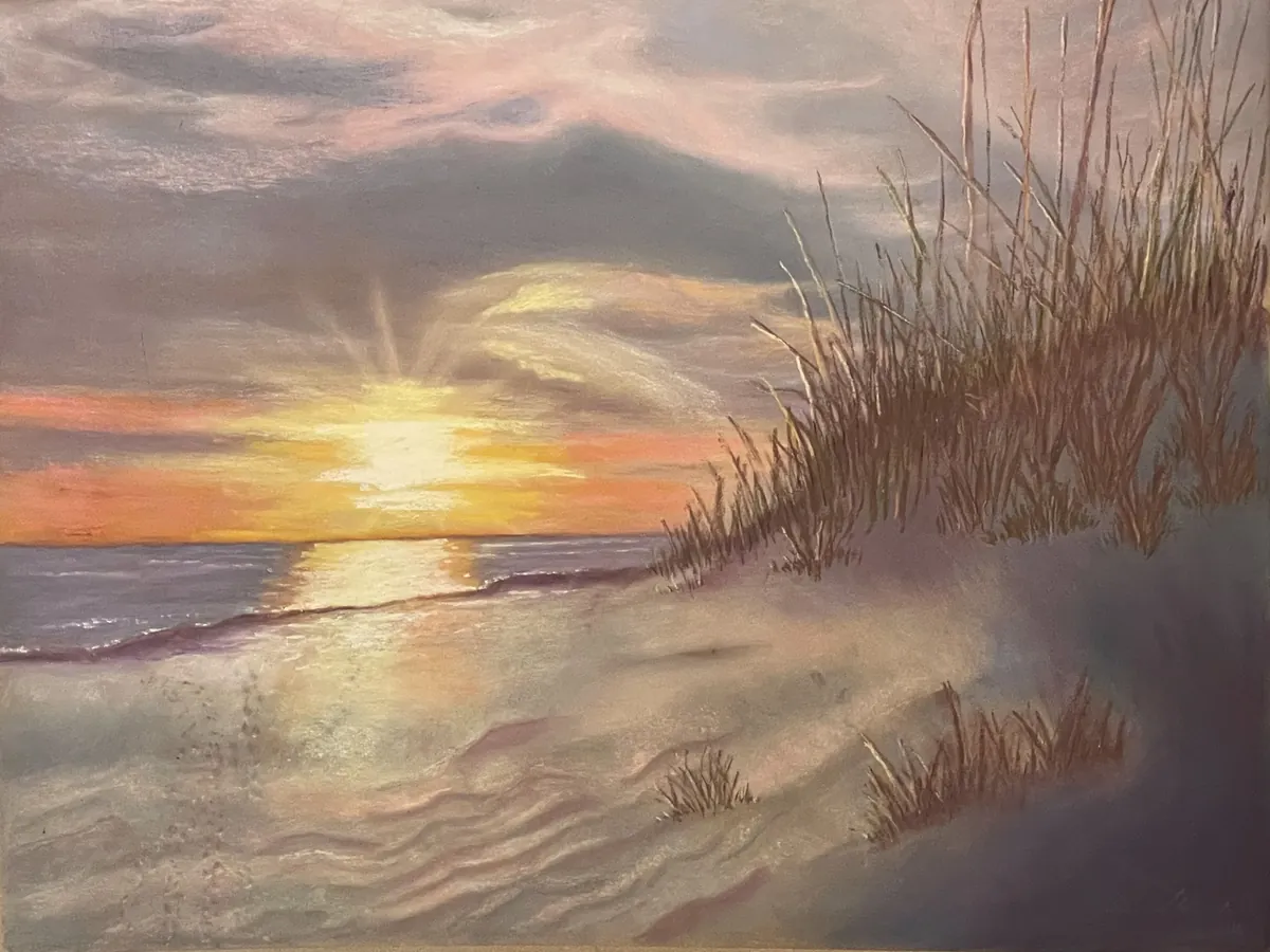 Golden sunset over a quiet beach, with reflected surf and tall dune grass
