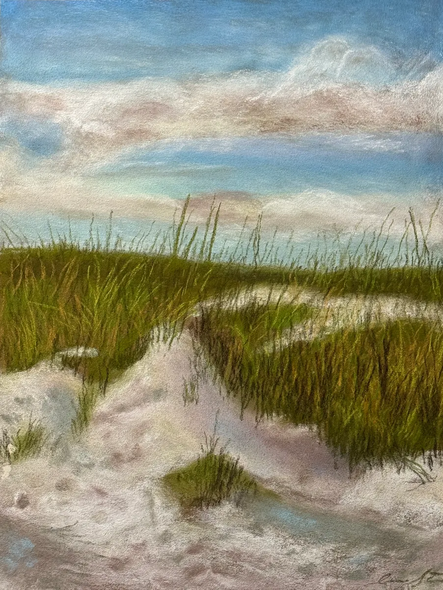 Sandy path through beach grass beneath a blue sky streaked with pale clouds