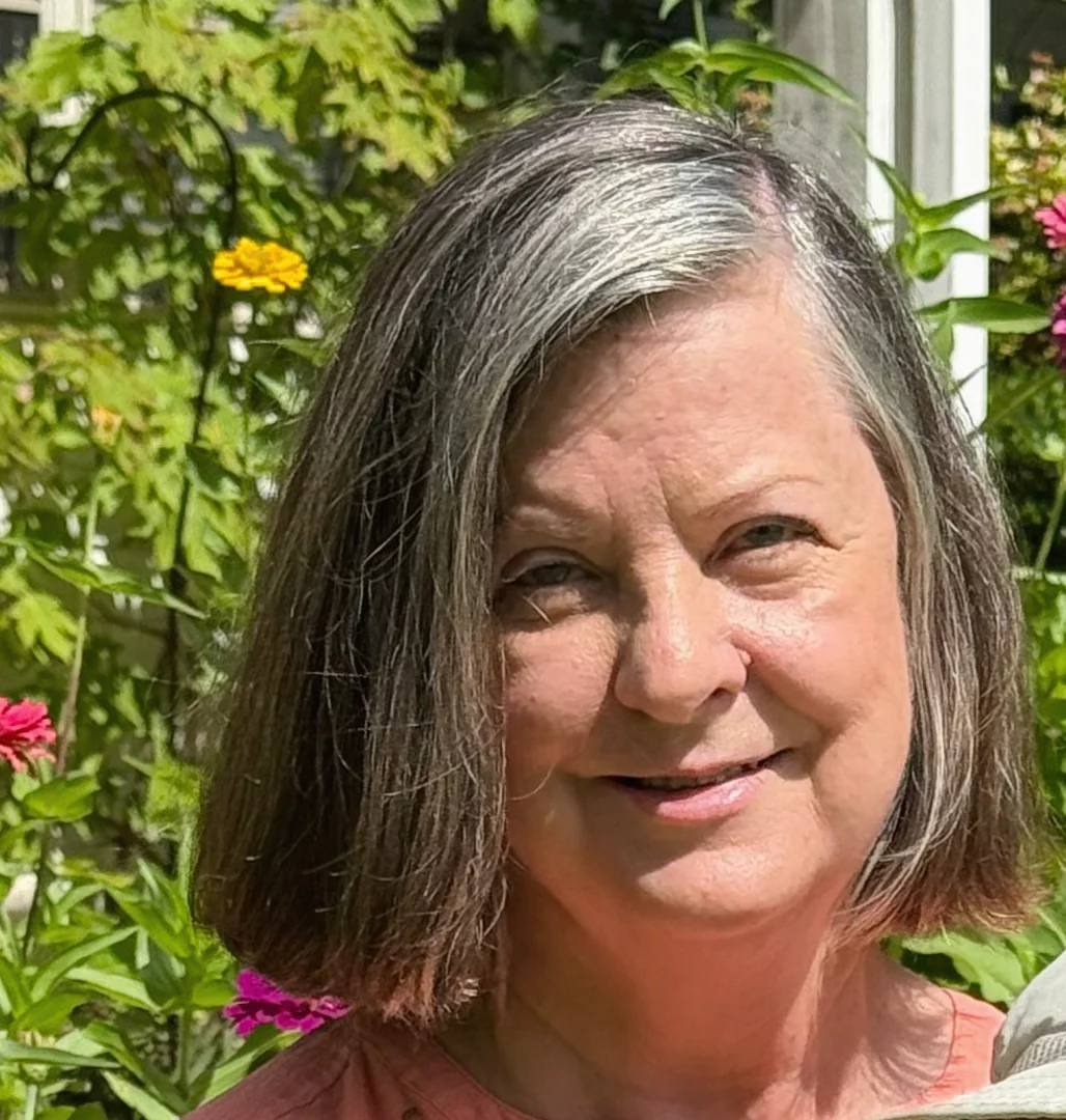 Anne Stewart smiling in a sunlit garden
